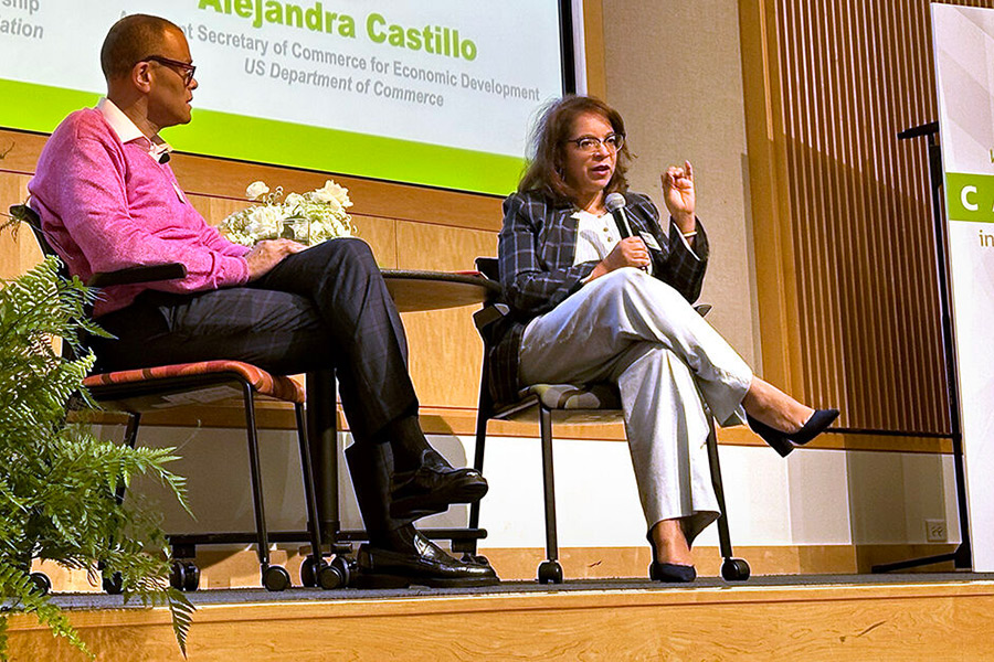 Alejandra Y. Castillo, Assistant Secretary of Commerce for Economic Development with the U.S. Department of Commerce, speaks into a microphone on stage at the Capital Innovation Summit. Philip Gaskin, vice president of Entrepreneurship with the Ewing Marion Kauffman Foundation, sits beside her on stage.