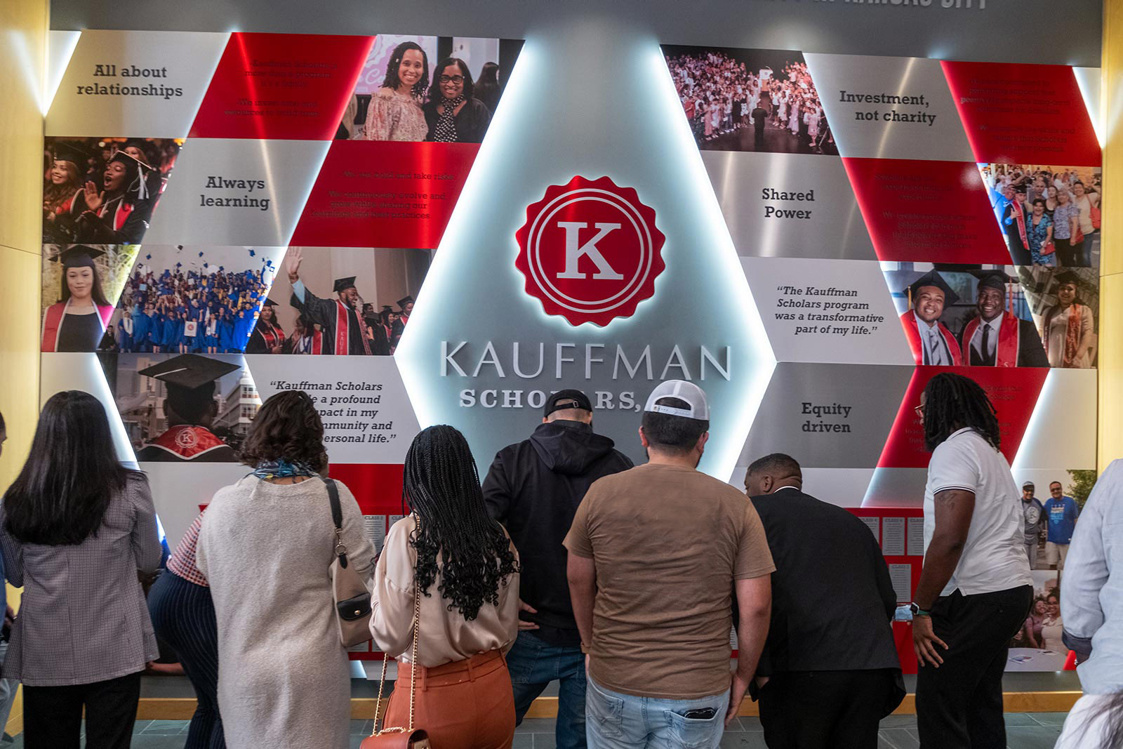 KSI alum stand in front of the KSI Legacy Wall after the ribbon-cutting ceremony.