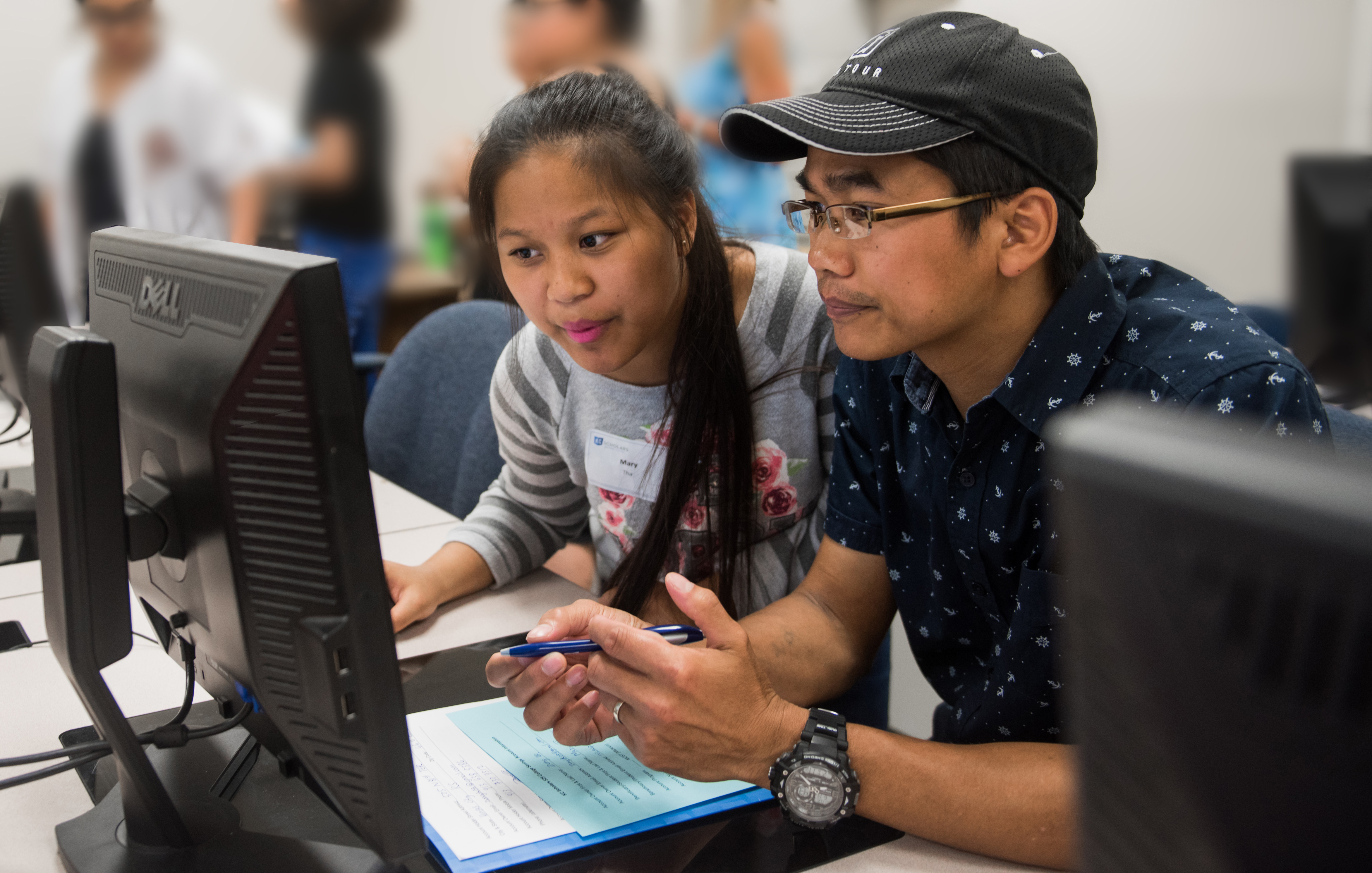 Two people sit in front of a shared computer